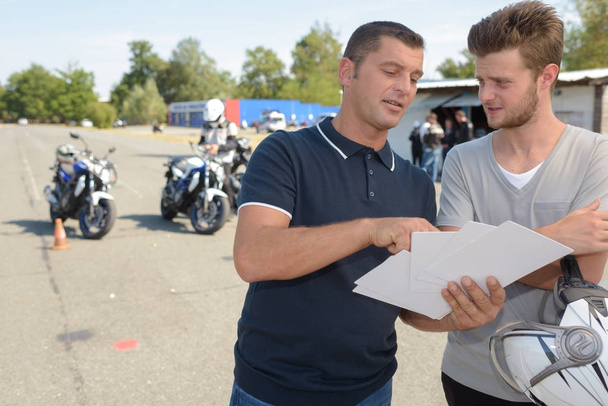инструктор по вождению разговаривает со студентом перед тестом на права на мотоцикл
 - Фото, изображение