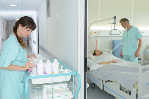 female nurse choosing products from trolley in hospital corridor - Foto, Imagem