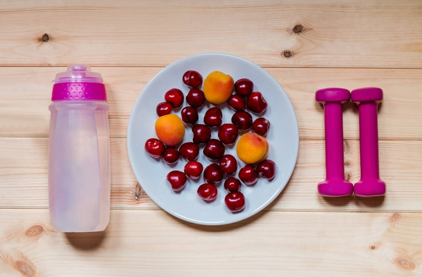 Sombrillas, botella de agua, frutas frescas sobre fondo de madera
. - Foto, Imagen