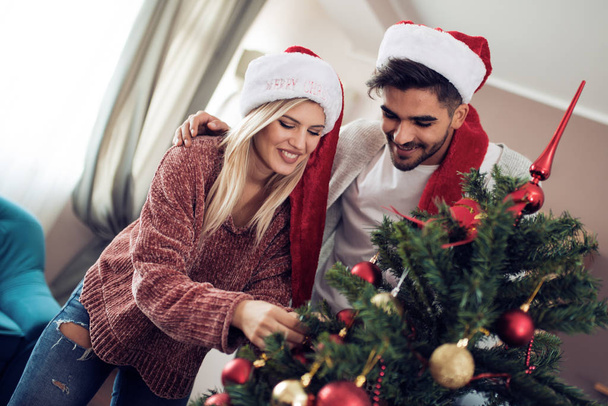 junges Paar schmückt einen Weihnachtsbaum - Foto, Bild