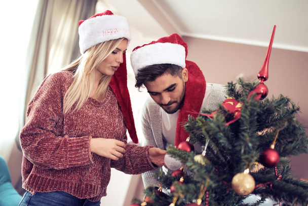 junges Paar schmückt einen Weihnachtsbaum - Foto, Bild