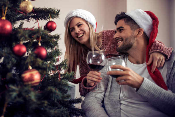 Ρομαντικό ζευγάρι με κόκκινο κρασί στο σπίτι. - Φωτογραφία, εικόνα