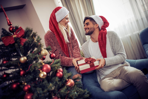 Young man giving his girlfriend Christmas present - Fotografie, Obrázek