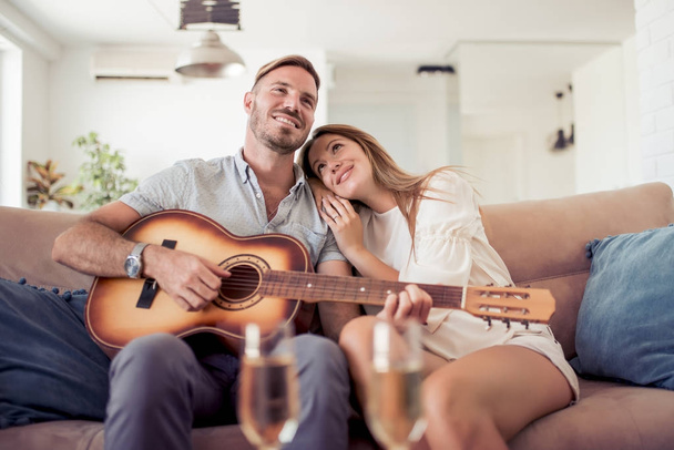 Man with acoustic guitar singing for smiling woman. - 写真・画像