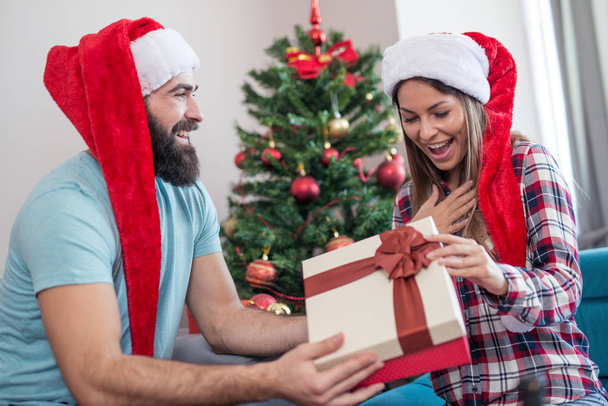 Молодой человек дарит своей девушке рождественский подарок
 - Фото, изображение