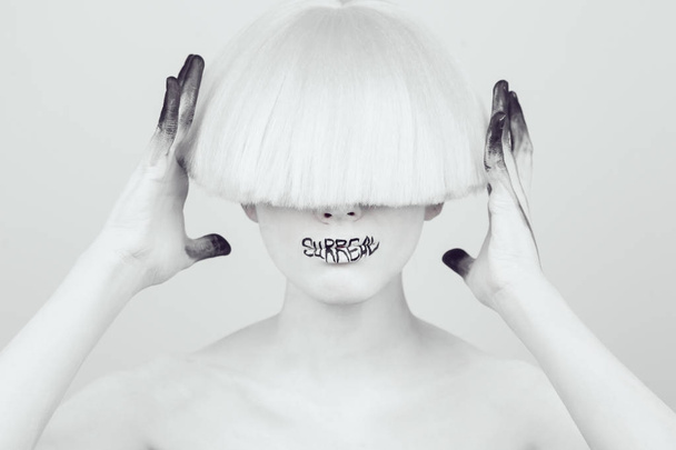 A girl with white skin and a white wig with an inscription on her lips surreal. - Фото, зображення