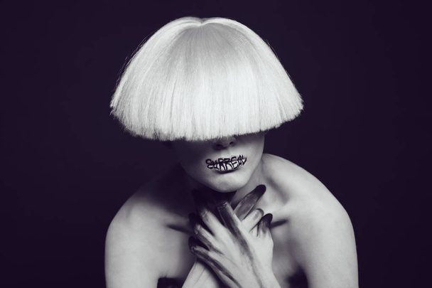 A girl with white skin and a white wig with an inscription on her lips surreal. - Photo, Image