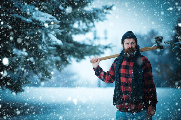 Christmas hipster lumberjack with ax in wood. - 写真・画像