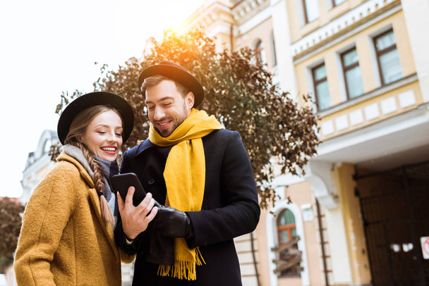 beautiful young couple in autumn outfit looking at smartphone - Photo, Image