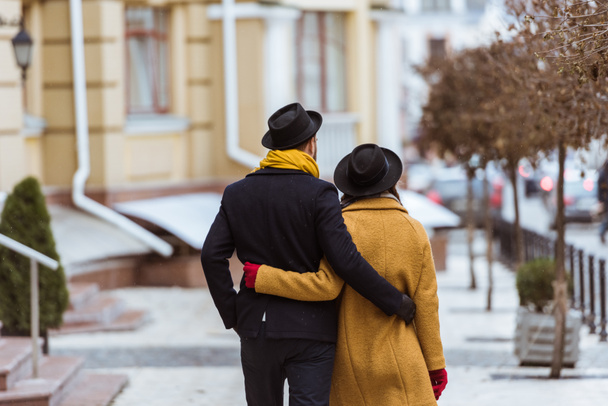 back view of young couple hugging and walking at street - Foto, afbeelding