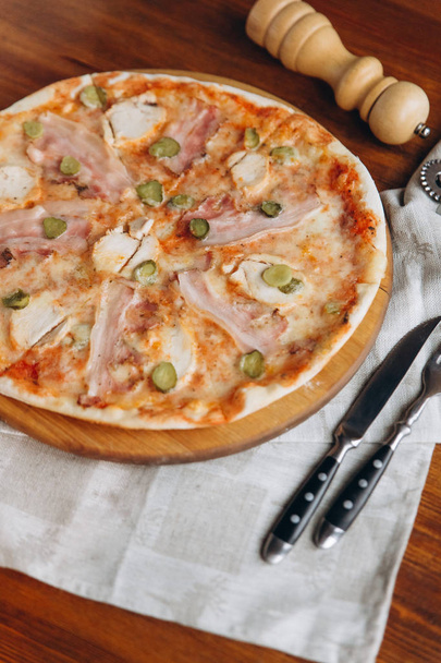 Sabrosa pizza de carne en una zanja de madera con servilleta de lino
  - Foto, Imagen