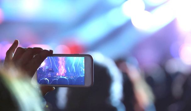νεαρό κορίτσι παίρνει μια φωτογραφία με το smartphone στη διάρκεια της συναυλίας - Φωτογραφία, εικόνα