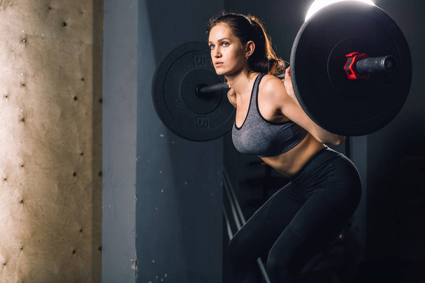 muscular woman in a gym doing heavy weight exercises with barbell - 写真・画像