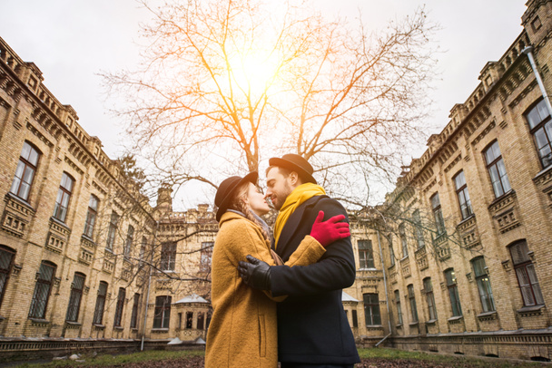 χαρούμενα ελκυστικό νεαρό ζευγάρι αγκαλιάζει μπροστά από το κτίριο - Φωτογραφία, εικόνα