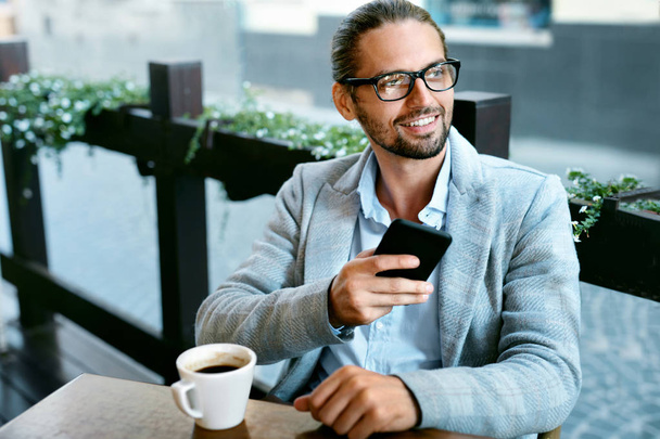 Man With Phone Drinking Coffee In Cafe - Фото, зображення