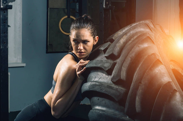 Strong girl flipping a tire in gym. - Fotoğraf, Görsel