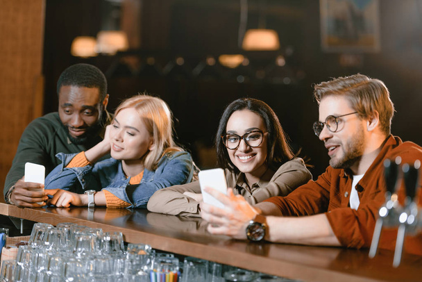 empresa atractiva joven en el bar mirando la pantalla de teléfonos inteligentes
 - Foto, imagen