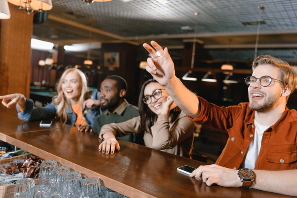 Молодые люди в баре звонят бармену
 - Фото, изображение