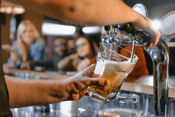 cropped image of barman pouring beer in glass at bar - Фото, изображение