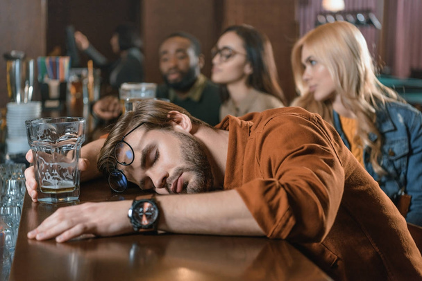 stark betrunkener junger Mann mit Freunden in Bar - Foto, Bild