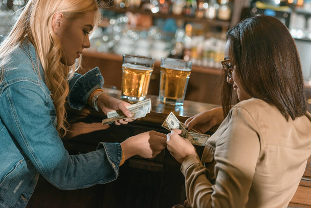 dos chicas con dinero pagando por la bebida en el bar
 - Foto, imagen