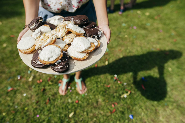 Высокий угол обзора женщины, держащей поднос с пончиками на газоне
 - Фото, изображение