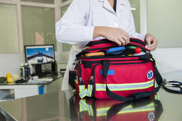 Seção média do kit médico de embalagem paramédica feminina no saco na mesa de metal
 - Foto, Imagem