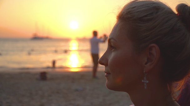 Retrato de cerca del perfil de la pacificada chica feliz al atardecer cerca del mar en la playa
 - Metraje, vídeo