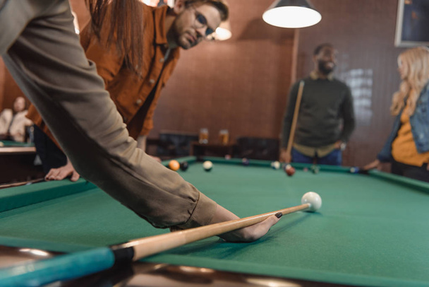 cropped image of young multiethnic friends playing in pool at bar - Foto, afbeelding