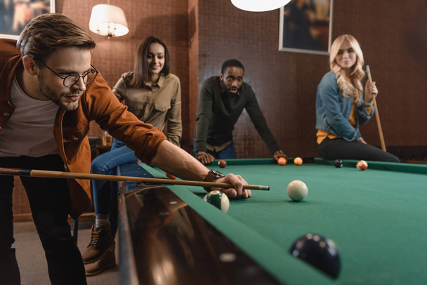 young attractive multiethnic friends playing in pool at bar - Foto, Imagem