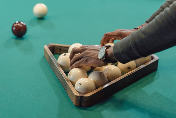 imagen recortada de manos masculinas formando bolas establecidas por triángulo en mesa de juego de billar
  - Foto, imagen