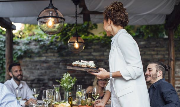 Woman Dinner Party Host Serving Food to Her Friends - Foto, Imagen