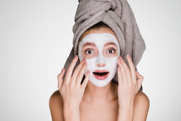 surprised beautiful girl takes care of herself, spa procedures, white face mask - Фото, зображення