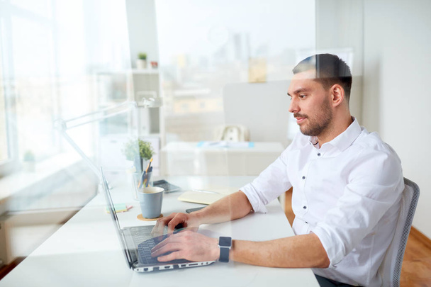happy businessman typing on laptop at office - Fotografie, Obrázek