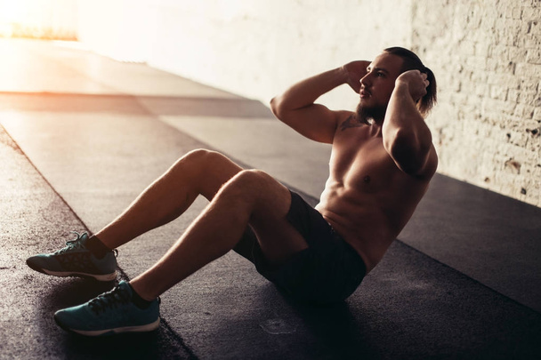 Muscular man exercising doing sit up exercise - Фото, зображення