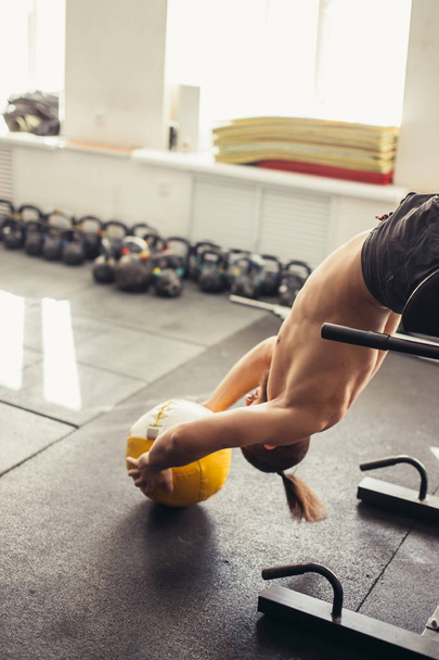 man doing sit ups with medicine ball on bench, working on abdominal muscles - Photo, Image