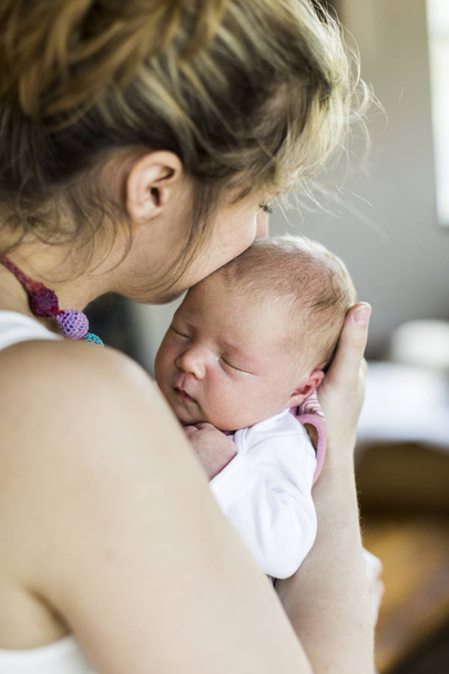 Young mother at home holding her newborn baby daughter - Fotoğraf, Görsel