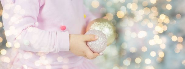 criança segura em mãos bolas de Natal
 - Foto, Imagem