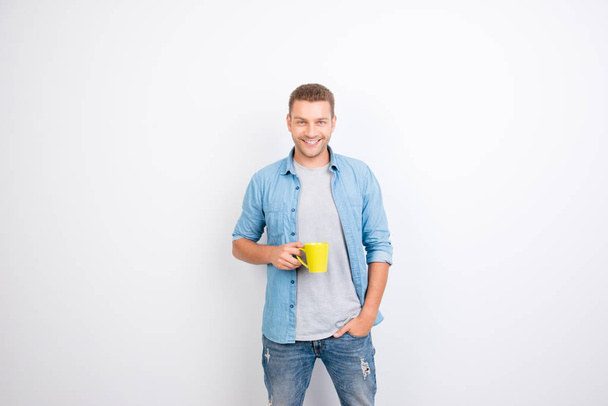 Portrait of cheerful, peppy guy holding yellow mug with coffee a - 写真・画像