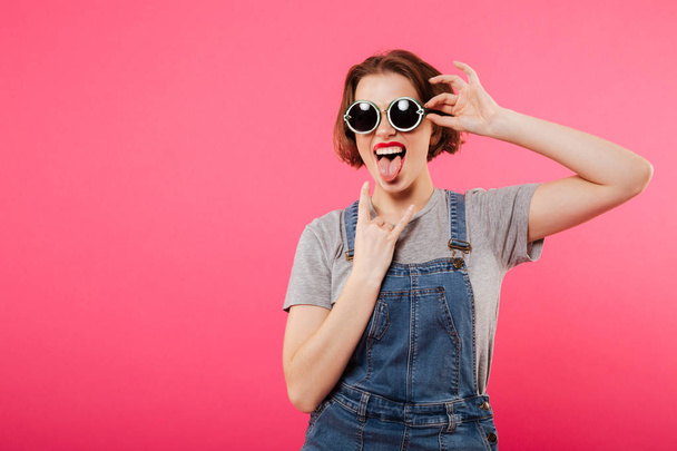 Cheerful young woman showing tongue and rock gesture. - Valokuva, kuva