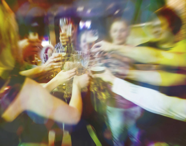 Blurred image. Group of best friends toasting with beer at cafe - Teenagers having fun eating pizza together at lunch time - Foto, Imagen