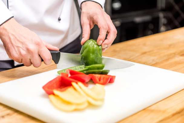 cropped image of chef cutting colored bell peppers  - Foto, Imagem