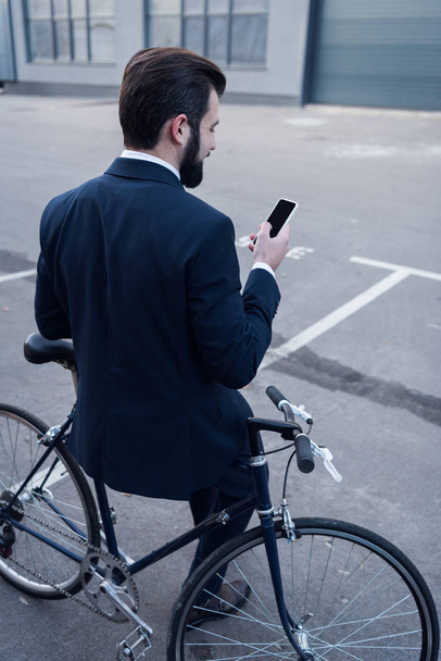 路上自転車にもたれながらスマート フォンを使用して実業家の背面図 - 写真・画像