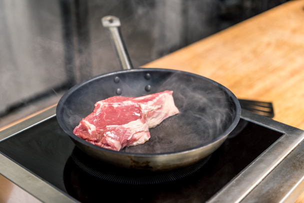 сырое мясо на сковороде на электрической плите
 - Фото, изображение