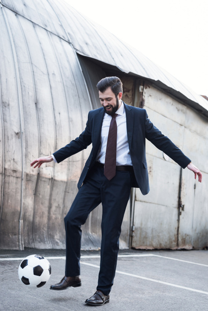 smiling businessman in suit playing soccer on street - Fotografie, Obrázek