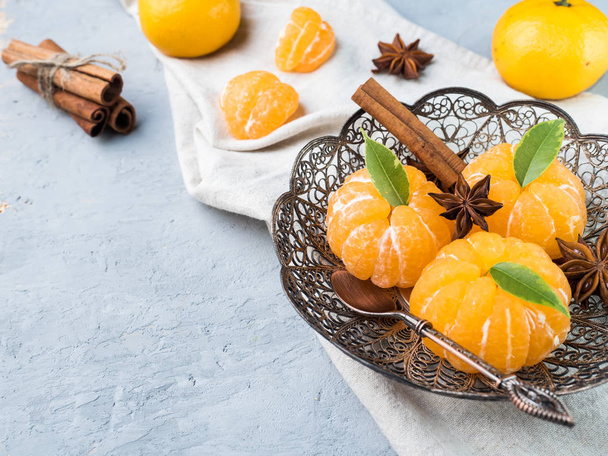 Fresh mandarins in a plate with fir tree branches, star anise cinnamon on gray background - Foto, afbeelding