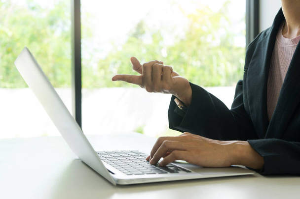 jeune femme asiatique travailler avec ordinateur sur le bureau ton blanc, son doigt pointe vers l'écran du portable
 - Photo, image