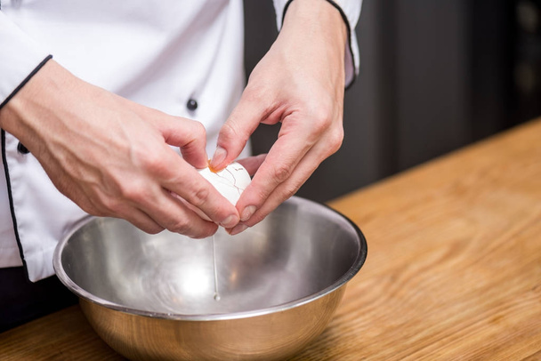 cropped image of chef putting egg into bowl - 写真・画像