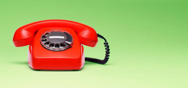 Red telephone in retro style on green background. - Фото, изображение