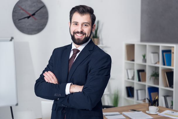 portrait of smiling businessman with arms crossed in office - Foto, afbeelding